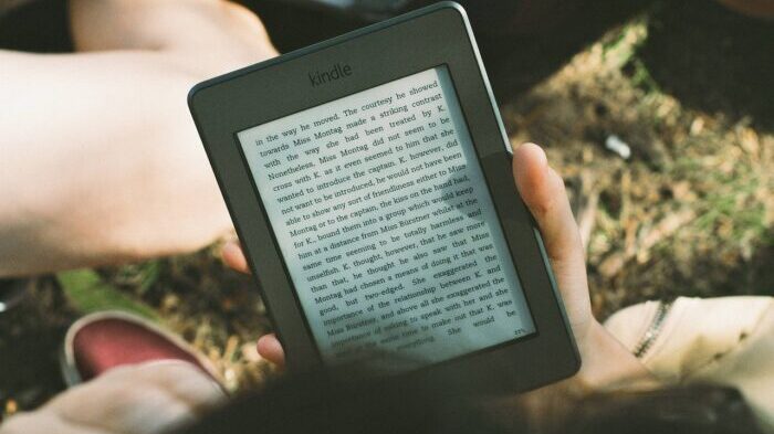 Vista por cima de um homem lendo um e-book em seu Kindle