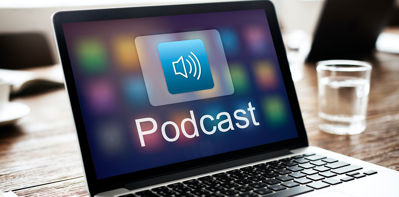 Foto de um notebook com a palavra 'Podcast' escrita em sua tela